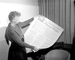 A black and white photo showing a woman holding a large print out with "Human Rights" on it